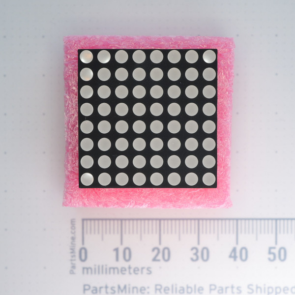 Top view of PARTSMINE A-1013 8x8 LED dot matrix display on pink foam next to a metric ruler.