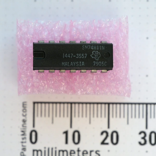 Top view of Texas Instruments 1447-3557 / SN74H11N 14-pin DIP integrated circuit with millimeter ruler.