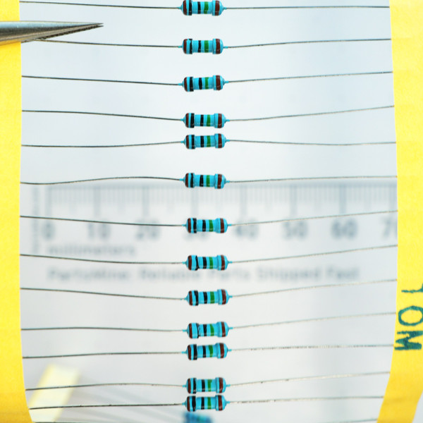 Strip of axial lead 10M ohm metal film resistors taped in parallel on yellow carrier tape.
