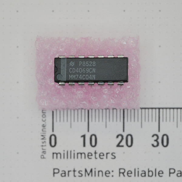 Top view of National Semiconductor CD4069CN DIP integrated circuit on ESD foam against a millimeter scale.