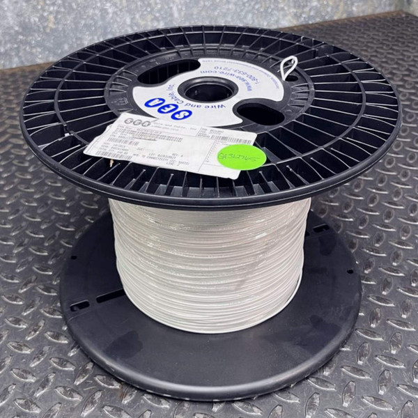 Spool of white SEA Wire and Cable M22759/32-16-9 hook-up wire standing on a metal surface.