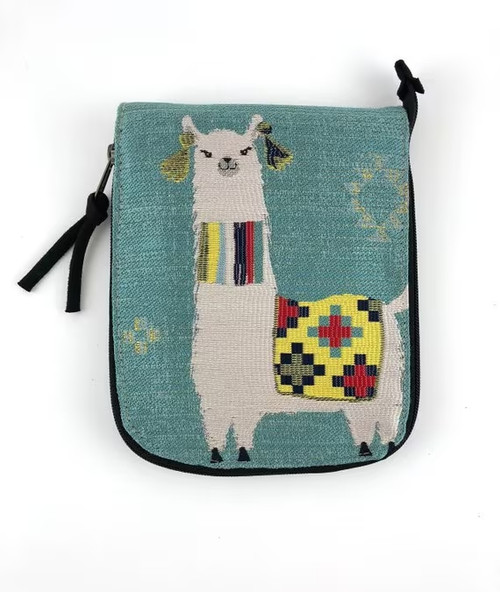 It’s a small turquoise fabric pouch with a side zipper and a playful embroidered llama design. The llama is stitched in white thread and wears a colorful woven blanket on its back, featuring bright squares of yellow, red, blue, and black. Tassels hang from its ears, and a striped scarf wraps around its neck, adding a cheerful touch. Decorative patterns are scattered around the background, giving the pouch a handmade, whimsical charm that feels both artistic and fun.