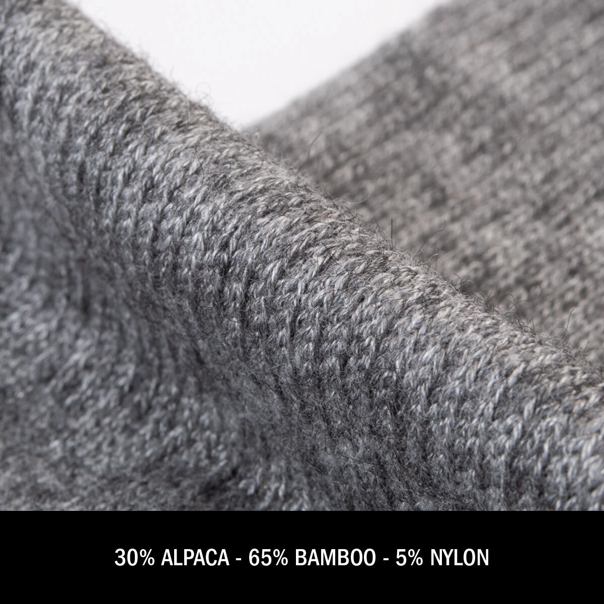 Close-up texture of grey knit alpaca sock fabric. Text below: 30% Alpaca - 65% Bamboo - 5% Nylon.