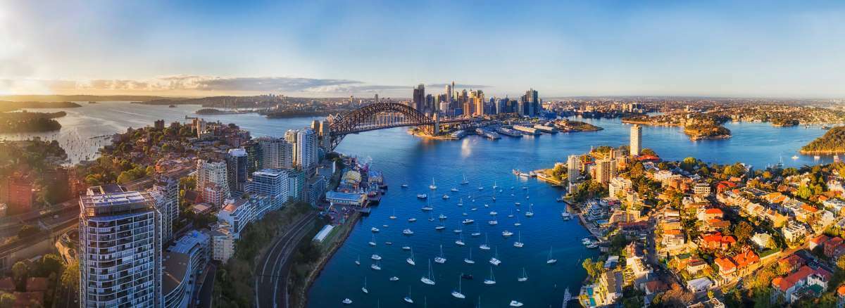 Aerial view of Sydney skyline with iconic landmarks like Sydney Opera House and Sydney Harbour Bridge.