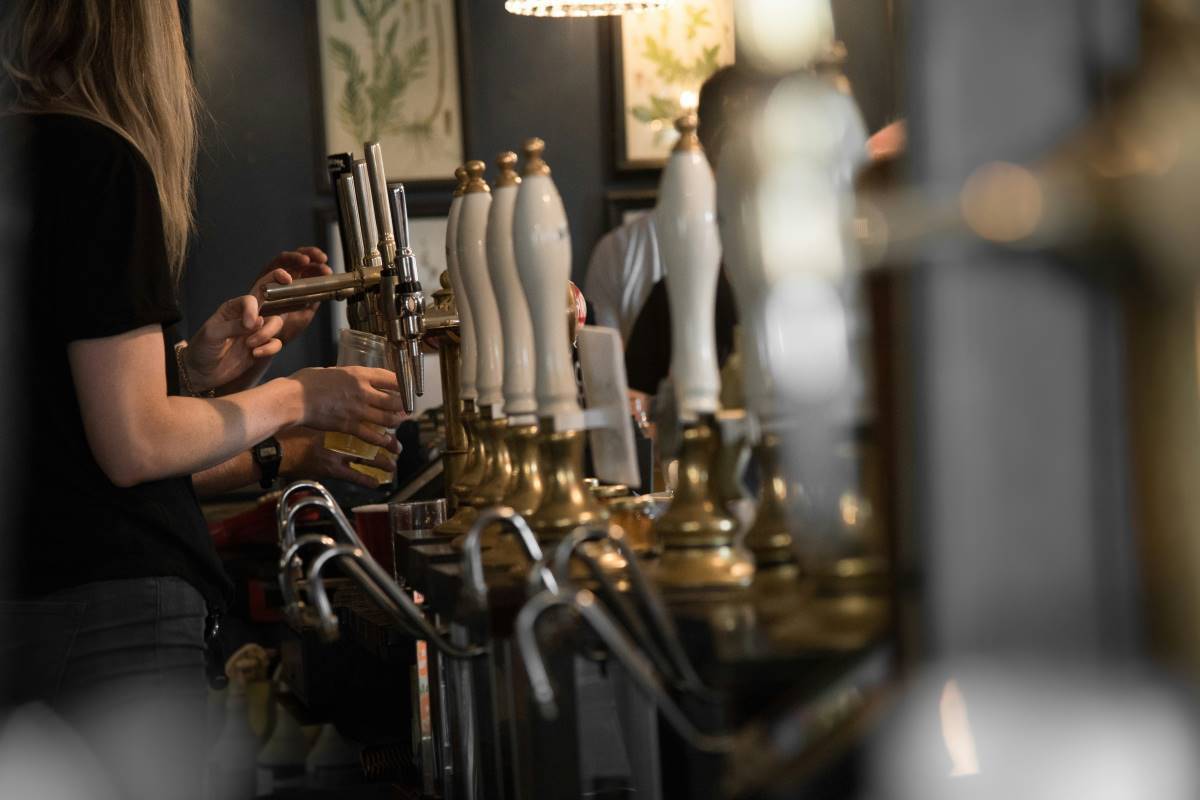 A woman pouring beer into a glass.