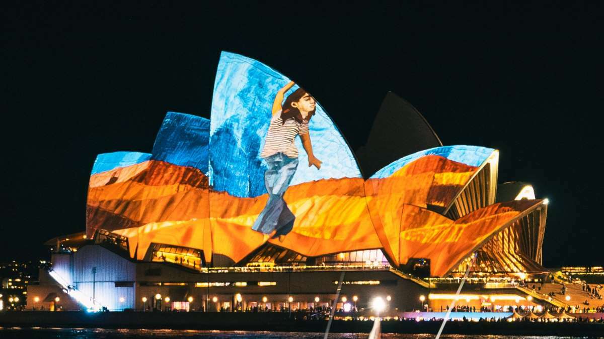 The Sydney Opera House illuminated in a vibrant display of colours at night.