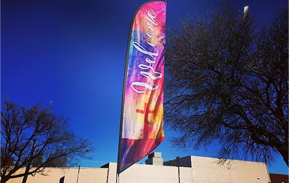 Colorful Easter feather flag against a blue sky outside a church