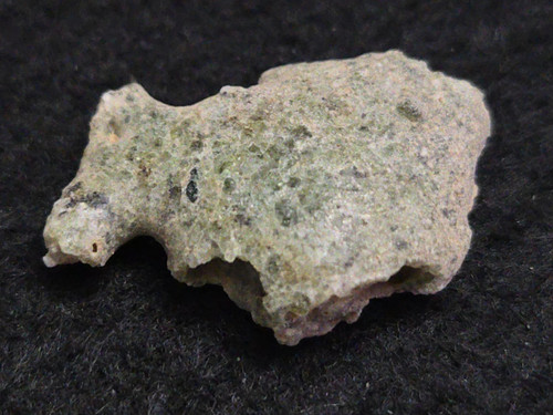 1.5 gram Trinitite specimen on display under indoor light