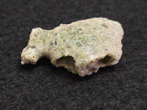 1.5 gram Trinitite specimen on display under indoor light