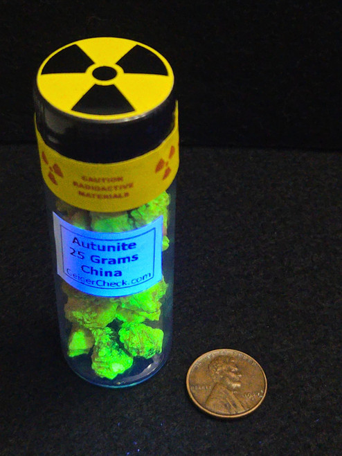 25 Grams of Autunite Fragments in a Glass Vial under UV light and size comparison