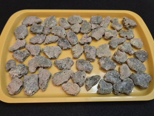 Trinitite Lot 1/4 lb 54 pieces, each smaller than 4 grams. on a yellow tray