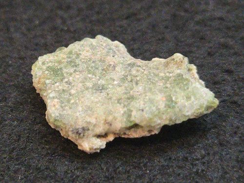 1.5 gram Trinitite specimen displayed under indoor light