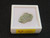 1.5 gram Trinitite specimen displayed under indoor light in labeled display case top view