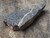 black bubbly botryoidal uraninite on matrix under outdoor light