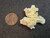 yellow boltwoodite on white gypsum matrix under indoor light size comparison to copper penny top view