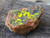 yellow splotchy Uranopilite after black  Uraninite  on  rust colored feldspar matrix under outdoor light