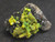 green autunite on black quartz matrix under indoor light