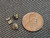 4 piece black uraninite specimens under indoor light size comparison to copper penny top view