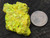 yellow/green 14 Gram autunite crystal under outdoor light size comparison to copper penny bottom view