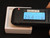Thoriated Glass Lens Element in white labeled display case measured by the Radiacode 102