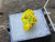 Yellow-green tabular autunite in perky box under outdoor light