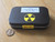Showing how the specimens are packed and shipped in a black metal tin with label and yellow and black round trefoil symbol