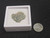 size comparison of vitreous trinitite in display case to steel penny top view