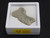 This vitreous looking trinitite specimen displayed in white plastic display case top view