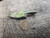 bright yellow Andersonite  & green Schröckingerite spatters  on grainy sandstone matrix under outdoor light size comparison to copper penny top view