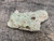 This vitreous looking greenish grey 3.1 gram trinitite specimen under outdoor light rotated