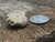 vitreous greyish green trinitite sample under indoor light size comparison to steel penny side view inverted