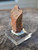 Drab reddish brown columnar Monazite-(Ce) crystal on display under outdoor light