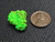bright fluorescent green lamellar autunite crystal under 365nm light and indoor light size comparison to copper penny top view