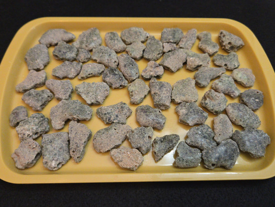 Trinitite Lot 1/4 lb 54 pieces, each smaller than 4 grams. on a yellow tray