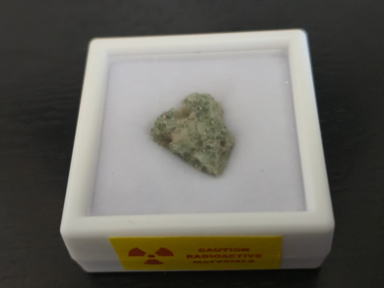 showing how Trinitite (Atomic Bomb Glass), 790 Milligrams is stored in labeled display case front view