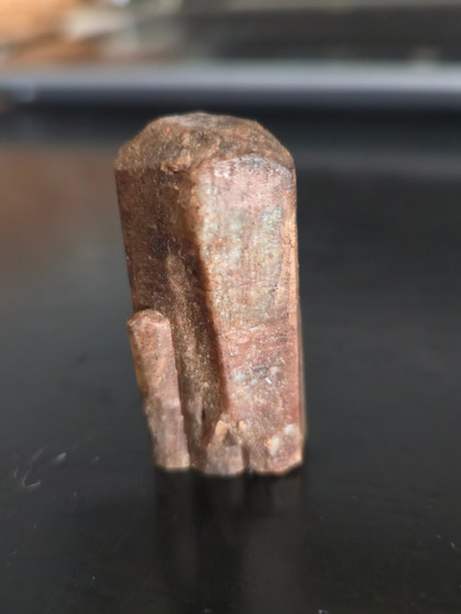 21 Gram red apatite crystal on display under indoor and outdoor light