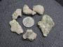 six piece Trinitite lot on display under indoor light size comparison to steel penny top view