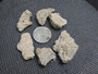 six piece Trinitite lot on display under indoor light size comparison to steel penny bottom view