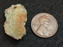 2.7 Gram Trinitite (Atomic Bomb Glass) specimen with red tinge under indoor light - size comparison to copper penny top view