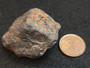 Columbite-(Fe)  under indoor light  SIZE COMPARISON TO copper penny top view