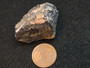 Tantalite-(Fe) - Petaca Mining District, New Mexico, USA under indoor light size comparison to copper penny bottom view