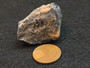 Tantalite-(Fe) - Petaca Mining District, New Mexico, USA under indoor light size comparison to copper penny top view