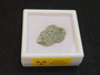 1.5 gram Trinitite specimen displayed under indoor light in labeled display case top view