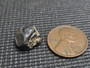 Uraninite  under indoor light size comparison to copper penny top view