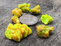 7 Piece Autunite Lot under outdoor light demonstrating daytime fluorescence size comparison to copper penny