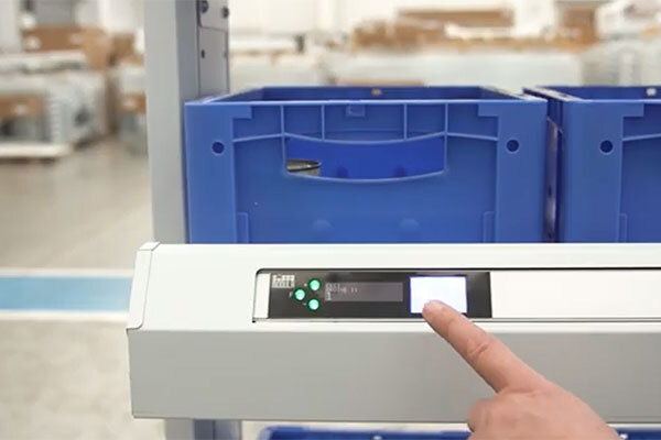 Order picker's hand presses a pick to light button after fulfilling an order