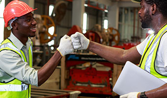 Two smiling warehouse employees share a fist bump in celebration.