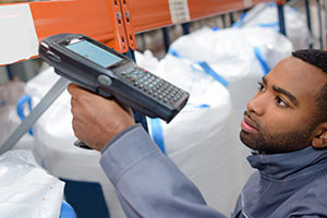 Warehouse worker uses a handheld scanner to read a barcode.