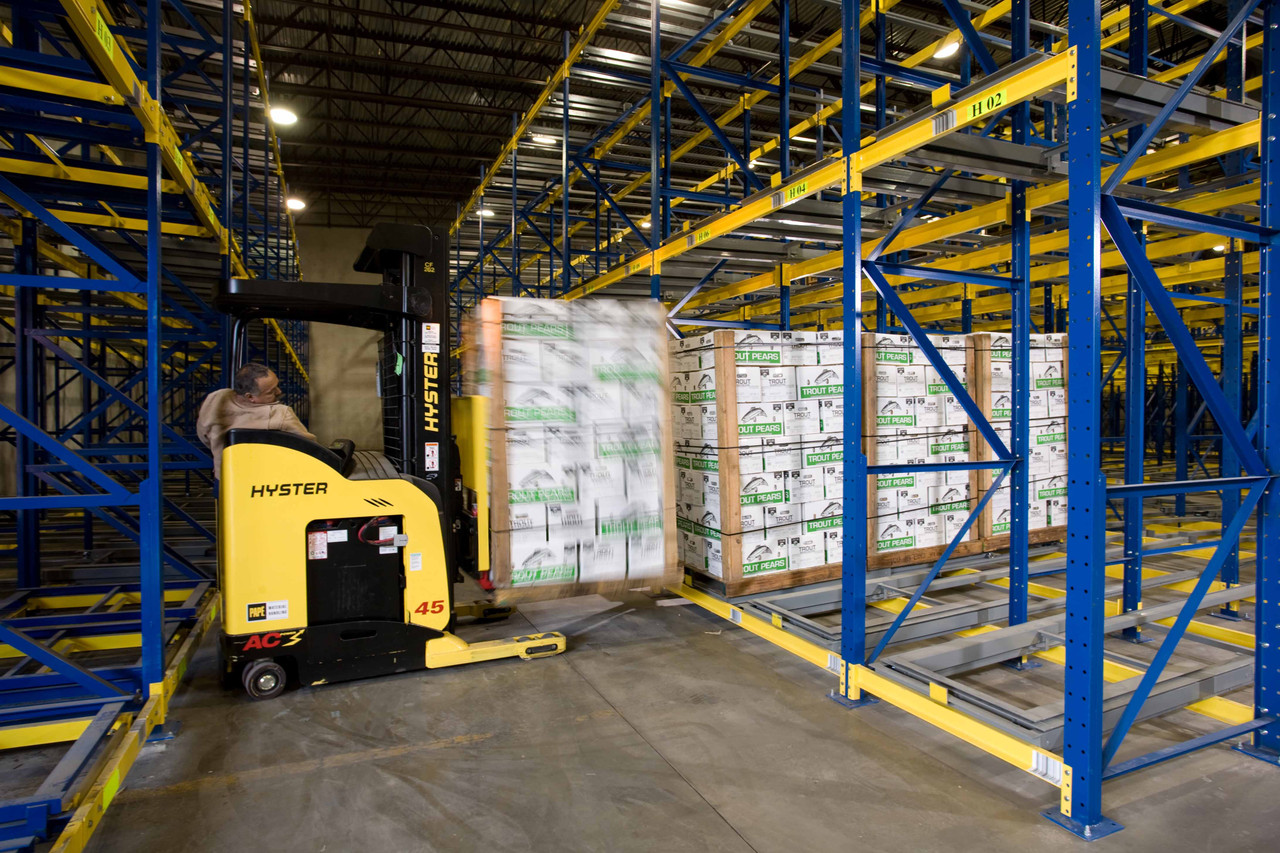 Image of forklift being operated by a professional to move heavy inventory inside a warehouse.