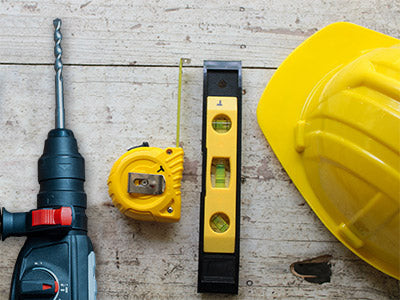 Make sure you have all the necessary tools and materials before installing custom material handling equipment. Tools photographed: a drill, tape measure, level, and safety helmet.